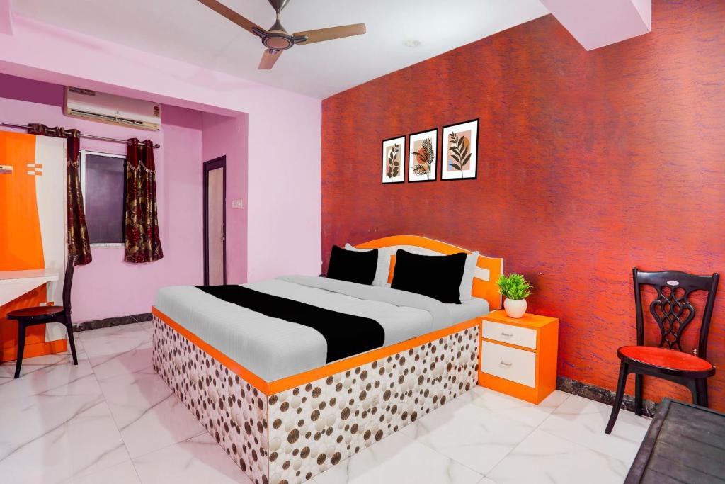 Un dormitorio con una cama con una pared naranja. en Hotel O The Triotel Inn, en Dhanbād