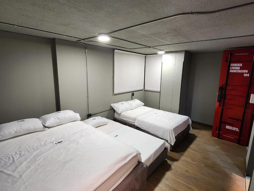 a room with two beds and a red door at Eureka Living in Bucaramanga