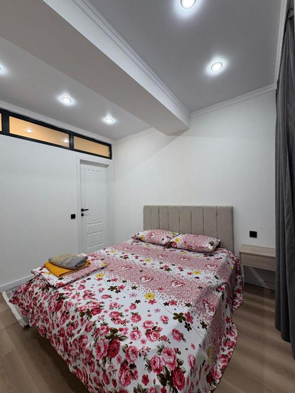ein Schlafzimmer mit einem Bett mit geblümter Tagesdecke in der Unterkunft Sunny Home Apartment in Almaty