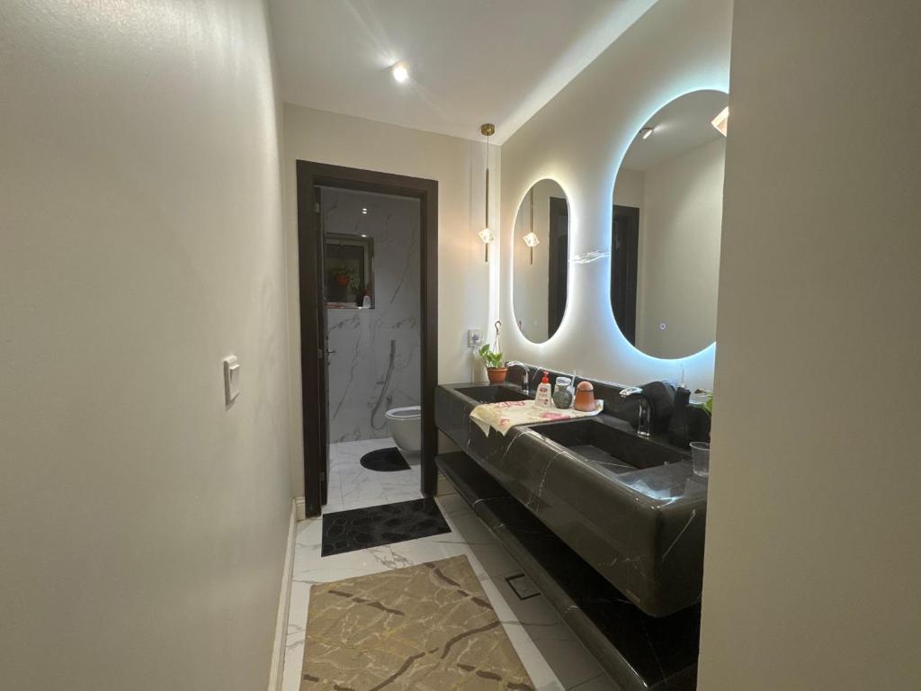 a bathroom with a black sink and two mirrors at استراحه و مجلس مدمجه in Riyadh