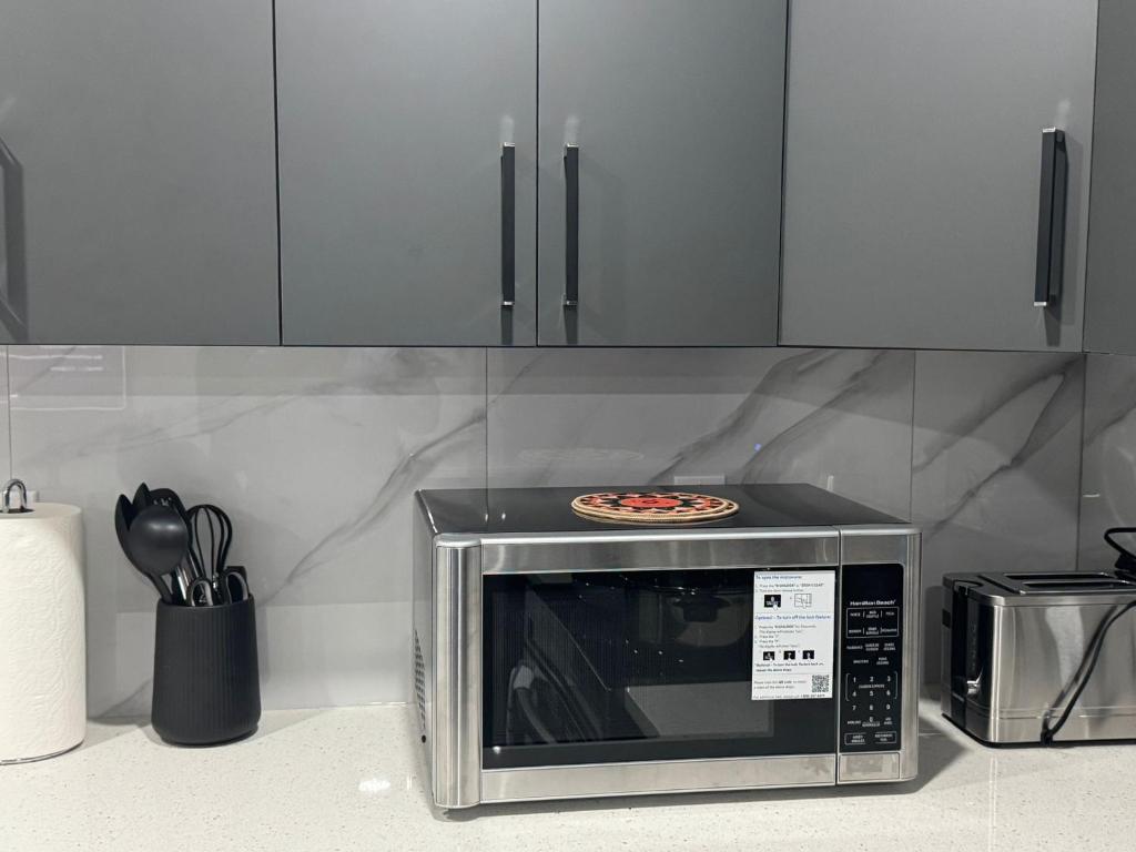 a microwave oven with a pizza on top of it at Modern comfort just 20 minutes from the airport, with a full kitchen in Edmonton