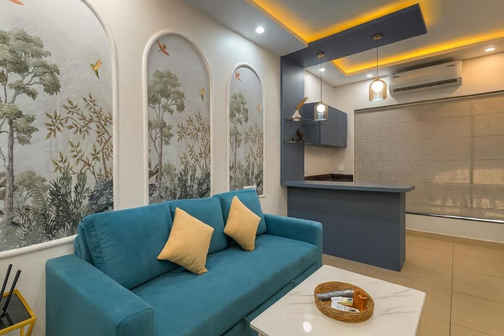 a living room with a blue couch and a kitchen at Sunset View High Floor Apartment with Pool & Jacuzzi in Siolim
