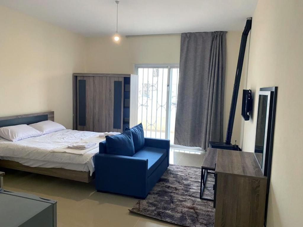 a bedroom with a bed and a blue chair at Chalet 101 - Zresidence - Faitroun in Al ‘Aqabah