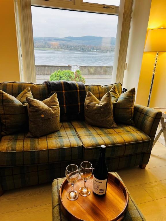 a couch with two wine glasses on a table at Angel Cottage, Strone in Dunoon
