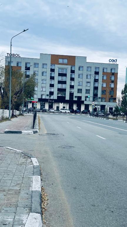 an empty street in front of a large building at Новая Евродвушка&Комфорт КЖБИ in Kostanay