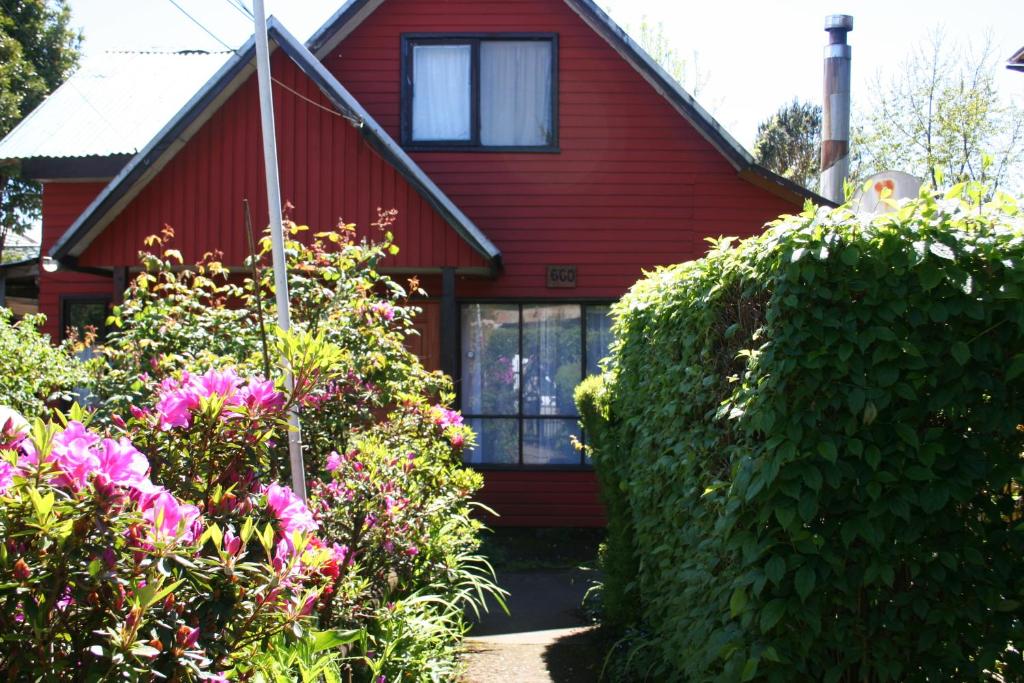 a red house with some flowers in front of it at Newendo Pucón in Pucón