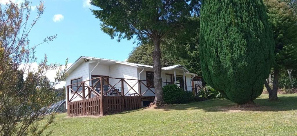 a white house on a hill with a tree at Cabaña en el campo in Puyehue