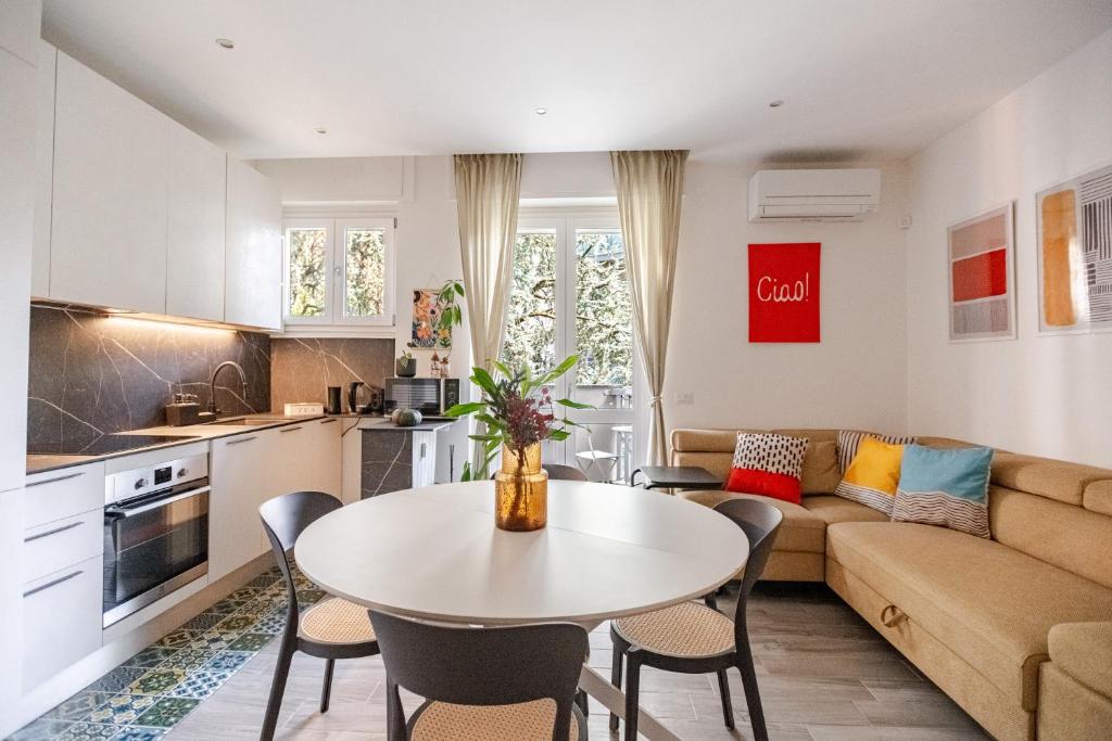 een keuken en woonkamer met een tafel en een bank bij Pomodoro House - Luminoso appartamento vicino Linate, Sky, Fabrique, Arena Santa Giulia in Milaan