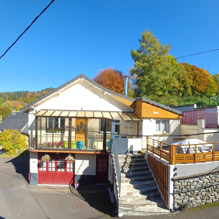 une maison blanche avec une porte rouge et un balcon dans l'établissement Les Planchettes, à Orcival