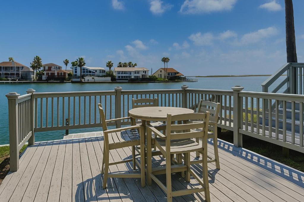 a wooden table and chairs on a deck with the water at Coastal Cozy and a View in Padre Island