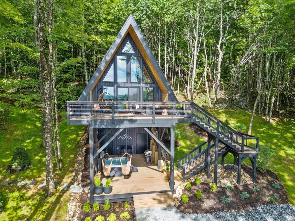 a tree house with a deck and a staircase at Ascent A-Frame at Calm Ridge Treehouses in Boone