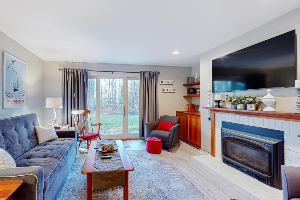 Una sala de estar con un sofá y una chimenea. en Salt Mountain Condo, en Warren