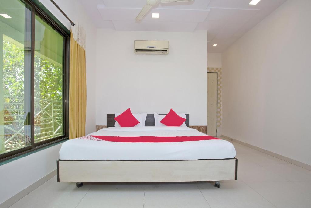 a bedroom with a large bed with red pillows at Hotel O Capital O Sai Icon Residency in Titwala