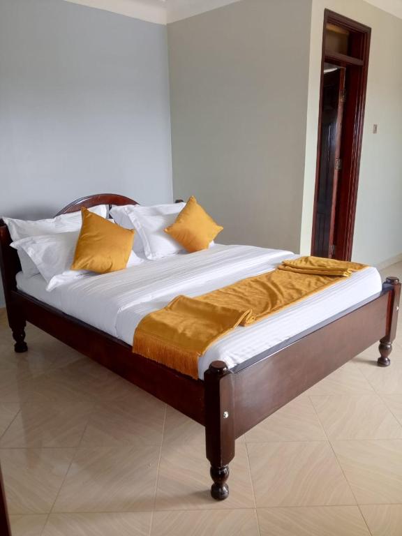 Una cama en una habitación con almohadas amarillas. en Ayeba Zion Hotel, en Fort Portal