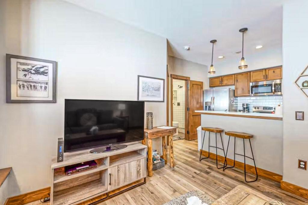 a living room with a large television and a kitchen at Los Pinos #D10 in Breckenridge