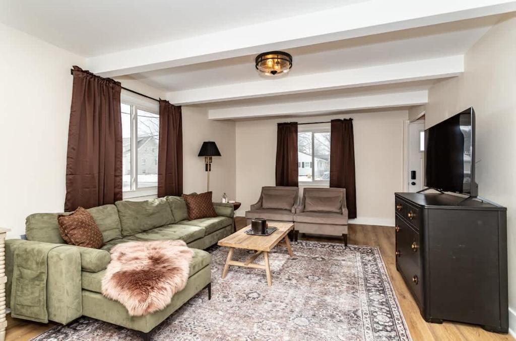 a living room with a green couch and a television at Modern 3BR Getaway-Stylish Ames in Ames