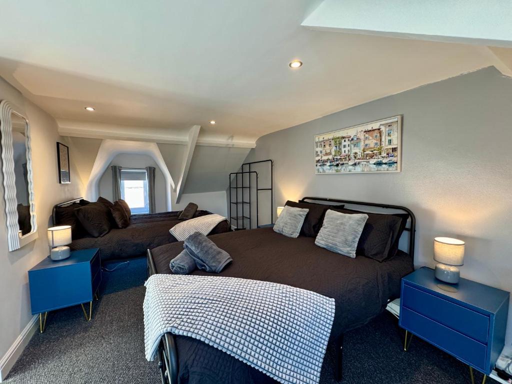 a bedroom with two beds and two blue tables at The Whitley Maisonette, Luxury Family Holiday Home in Whitley Bay