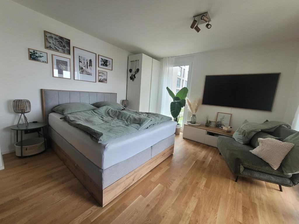 a bedroom with a bed and a tv and a chair at StyLE Apartment - perfekt für Messe, Flughafen, S-City in Leinfelden-Echterdingen