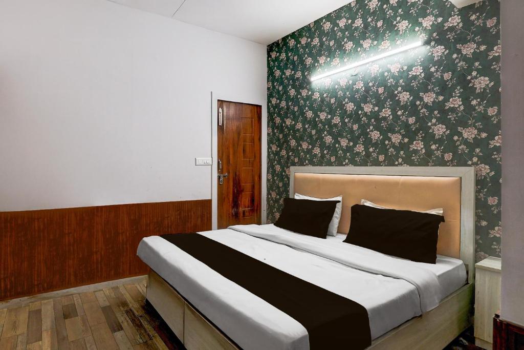 - une chambre avec un grand lit et du papier peint floral dans l'établissement Hotel O Square Residency, à Rājpur