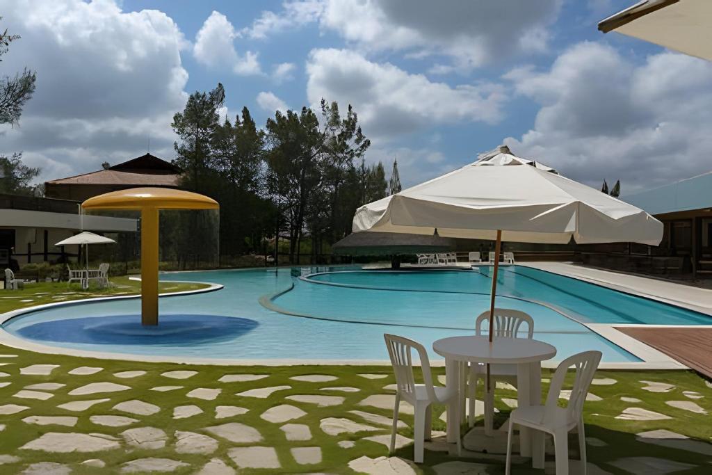 einen Pool mit Sonnenschirm, Tisch und Stühlen in der Unterkunft Flat de luxo no Monte Castelo - by Haus in Bezerros