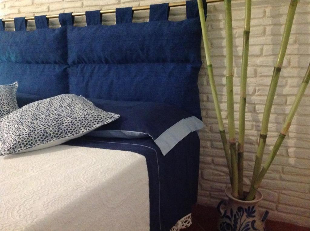 トッレ・パリにあるCasa Quintinaの青いシーツと植物の花瓶が備わるベッド