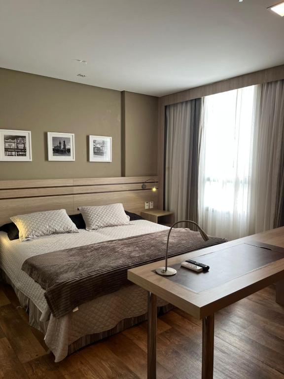 a bedroom with a bed with a table and a window at Flat Executivo Intercity Manaus - Moderno e Aconchegante in Manaus