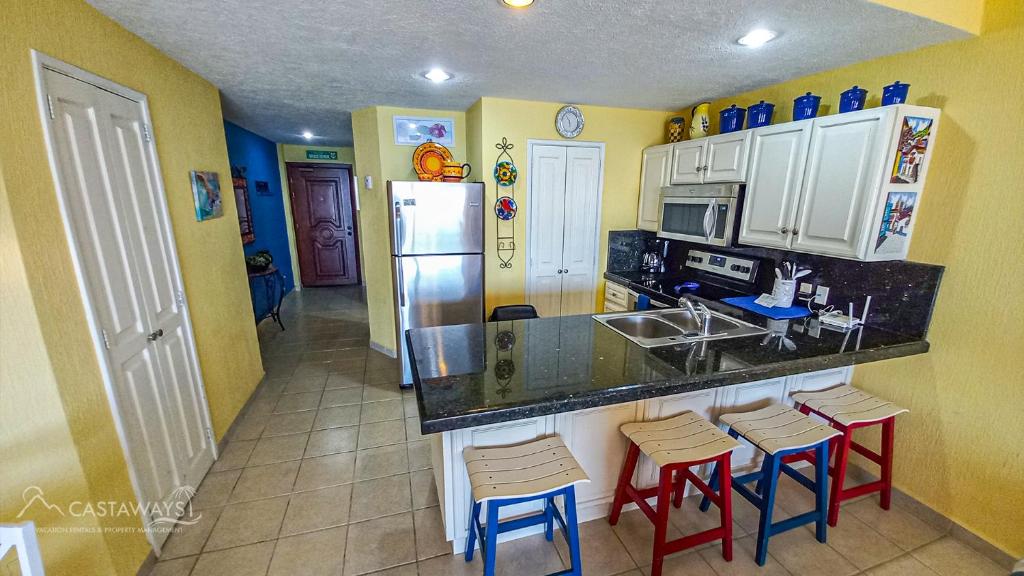 a kitchen with a counter with stools and a refrigerator at Sonoran Spa N603 in Campo del Medio