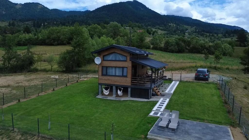 a house on a lawn with a car in the background at Recele Tiny Nest in Ilva Mare