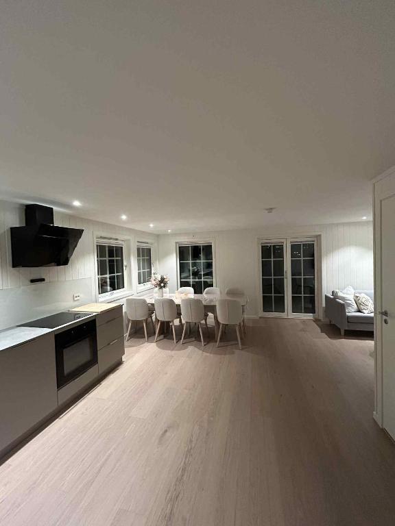 a white kitchen with a table and chairs in a room at Hytte med sjøen in Kristiansand