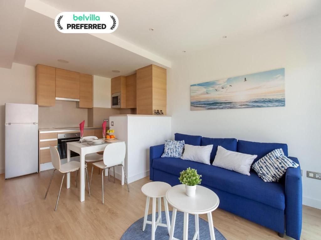 Una sala de estar con un sofá azul y una cocina. en Belvilla by OYO Modern Apartment in Palamos, en Palamós