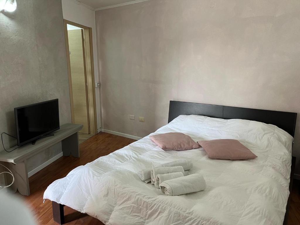 a white bed with two pillows and a television at S'Intrada in Thiesi