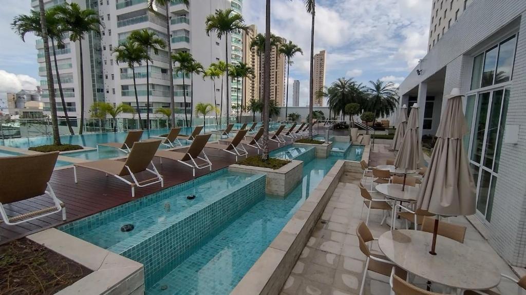 a swimming pool with chairs and tables and umbrellas at COP30 - Apê Amazônia Living - Sem reserva mínima - 4 Camas - Umarizal - Belém in Belém