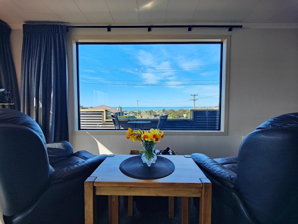 a living room with a vase of flowers on a table at Korimako Sea View Sanctuary in Riverton