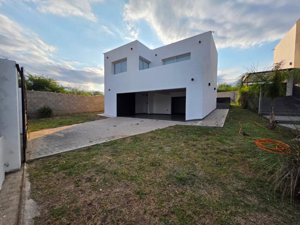 una casa blanca con un garaje grande en un patio en CountryHome Tierra Alta, en Villa San Nicolás