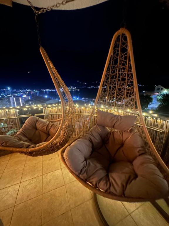 two hanging chairs on a balcony at night at Sea View Budva in Budva