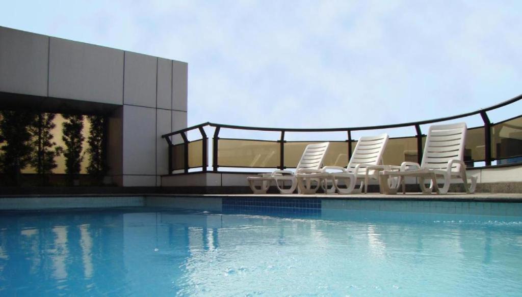 a group of chairs and a swimming pool at CONFORT iNN EXECUTIVE FARIA LIMA in Sao Paulo