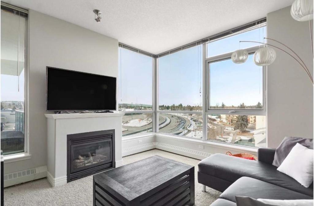 a living room with a fireplace and a tv at The Spruce Modern 2BR Condo with Pool & Parking in Calgary