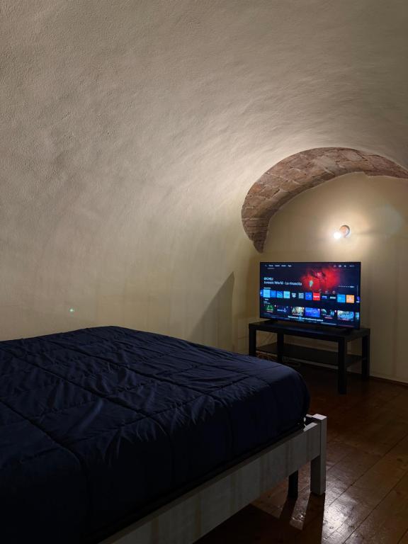 a bedroom with a bed and a flat screen tv at Living Adua Centro in Tortona