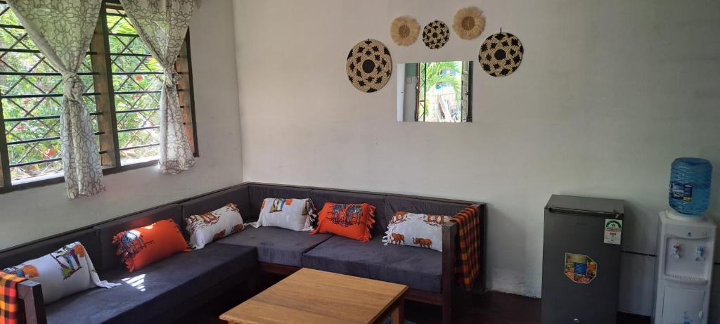 a living room with a couch with pillows and a table at Diani's Little Gem in Ukunda