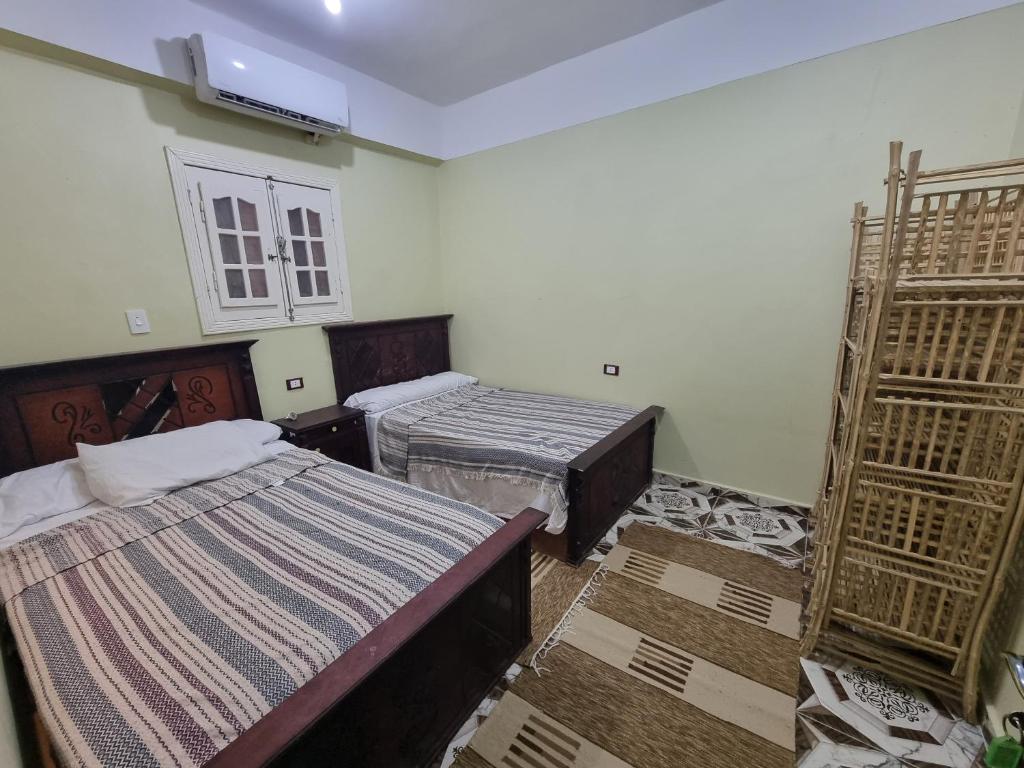 een kamer met twee bedden en een raam en een kluis bij Palm Apartments Siwa in Siwa