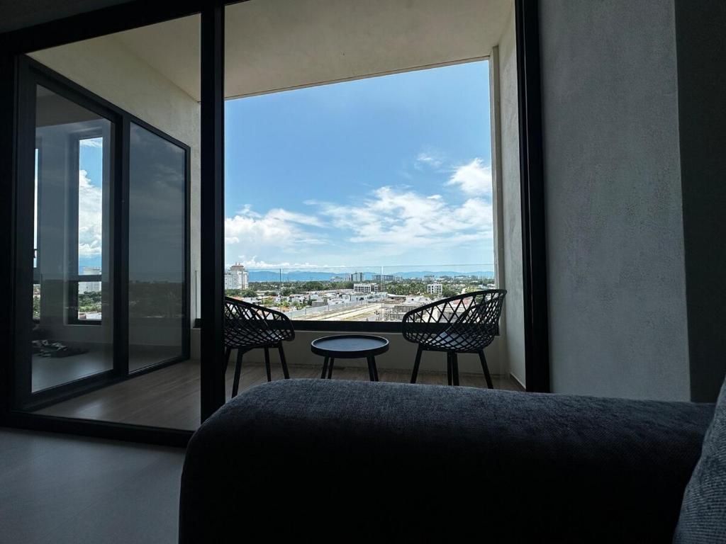 Habitación con ventana grande con 2 sillas y mesa. en Hermoso departamento 2 recámaras con alberca, en Nuevo Vallarta 