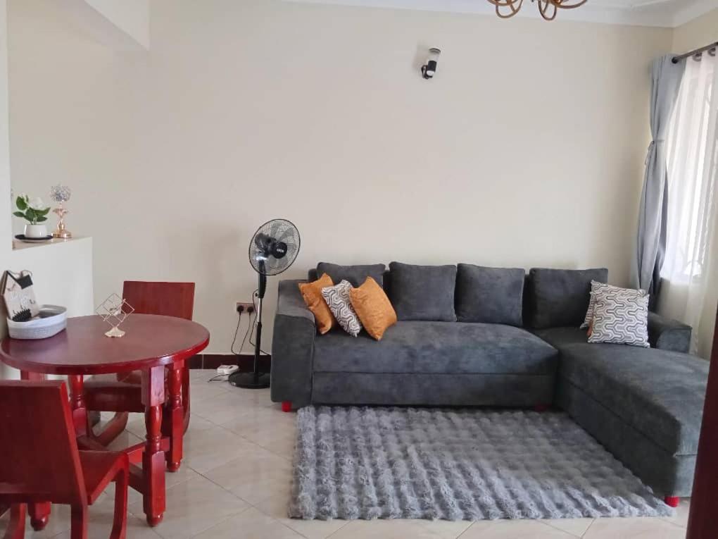 una sala de estar con un sofá y una mesa en Guest House Entebbe Road, en Namulanda