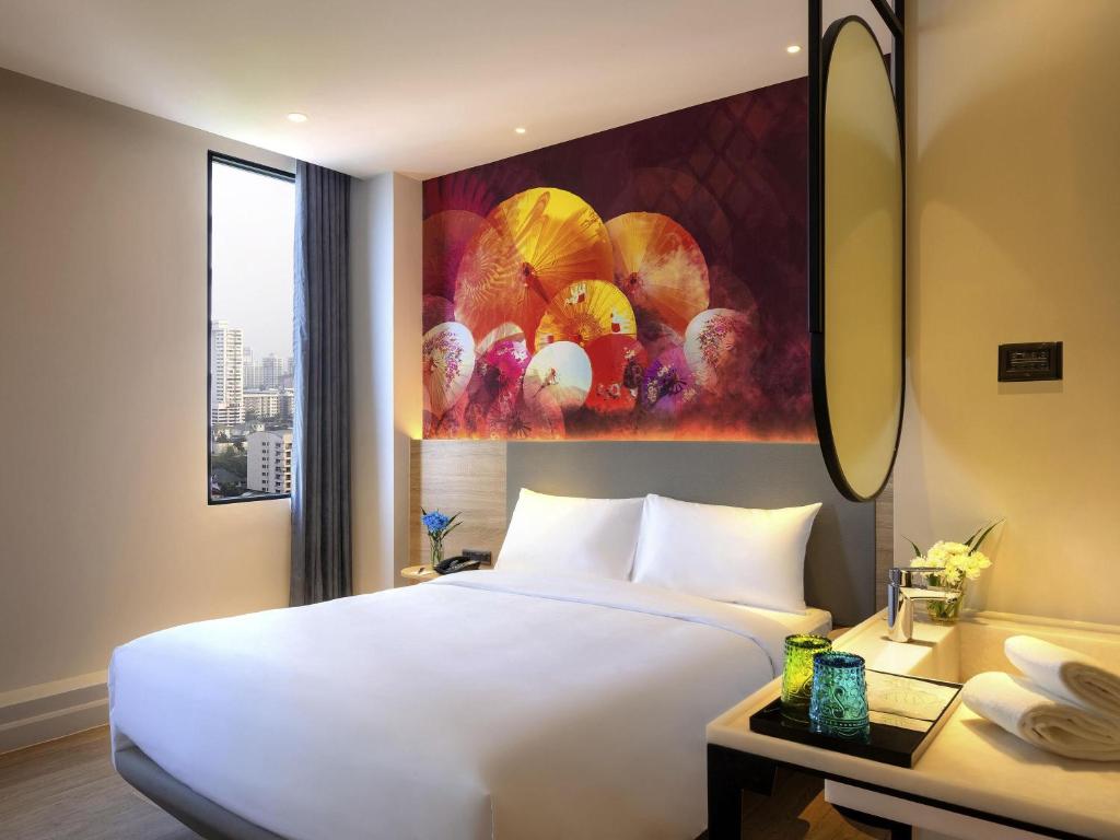 A double room has a city-facing window, colorful mural, and compact vanity.