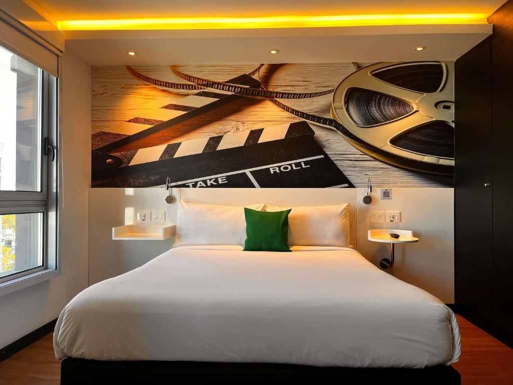a bedroom with a large bed with a painting on the wall at ibis Styles Montevideo Biarritz in Montevideo