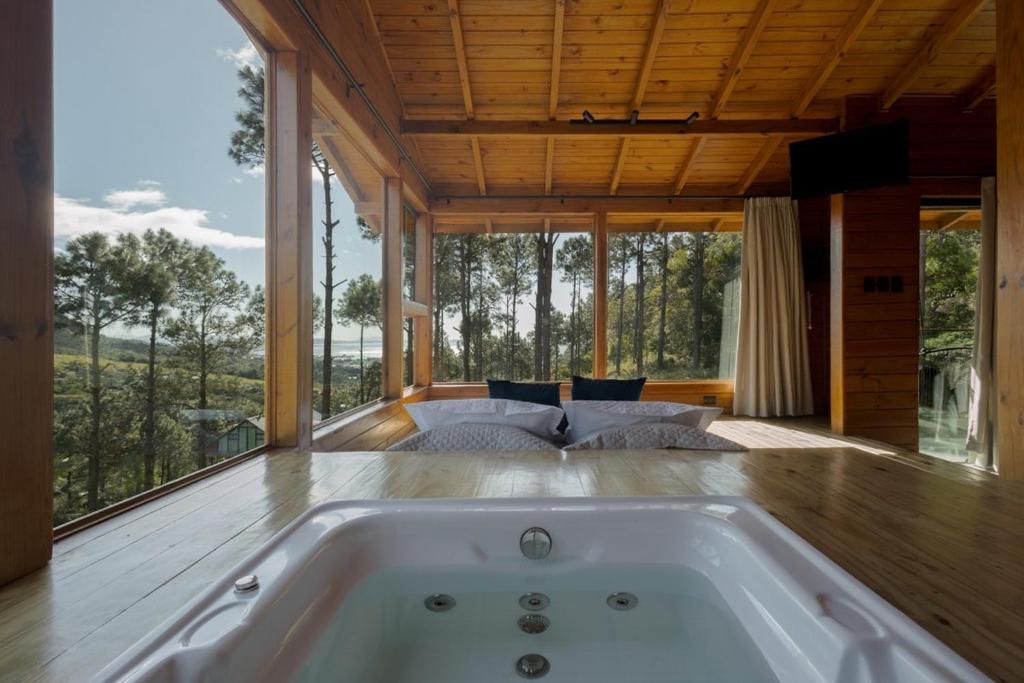 a bath tub in a room with a large window at Chalés Céu da Colina in Palhoça