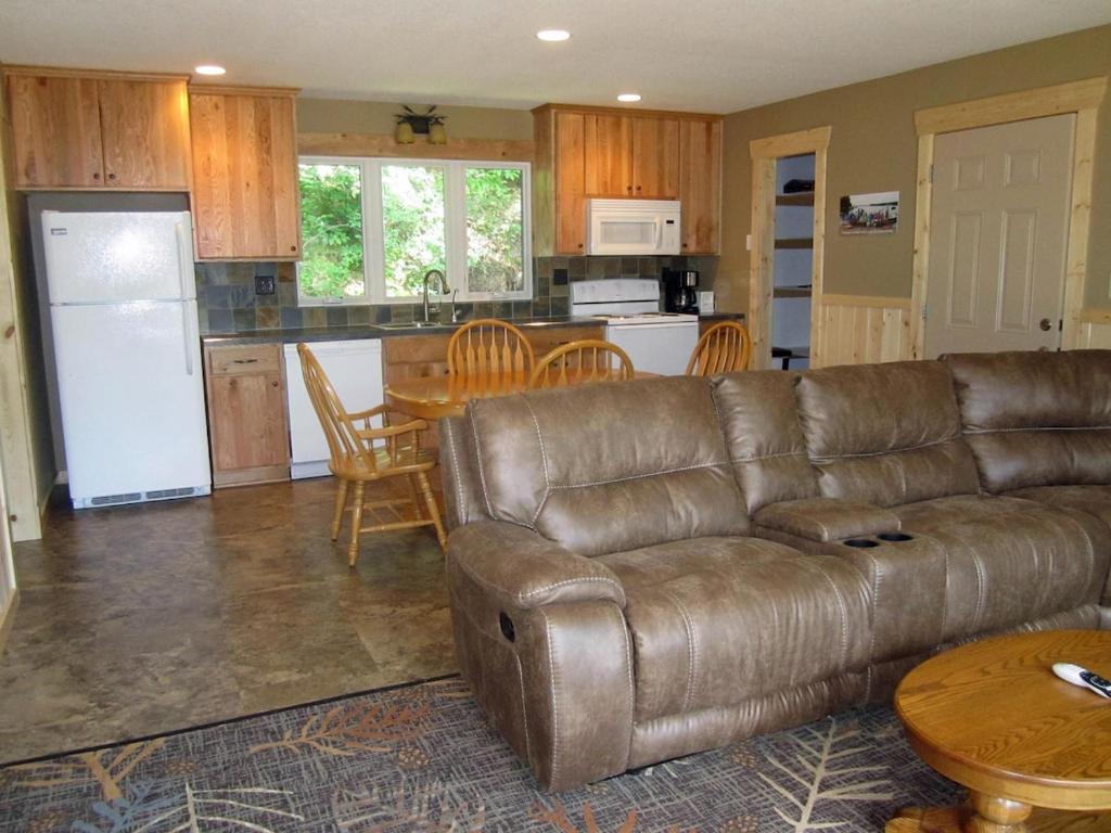 Una sala de estar con un sofá de cuero y una cocina. en Oak at Pine Cone Lodge - 1 large bedroom, en Park Rapids