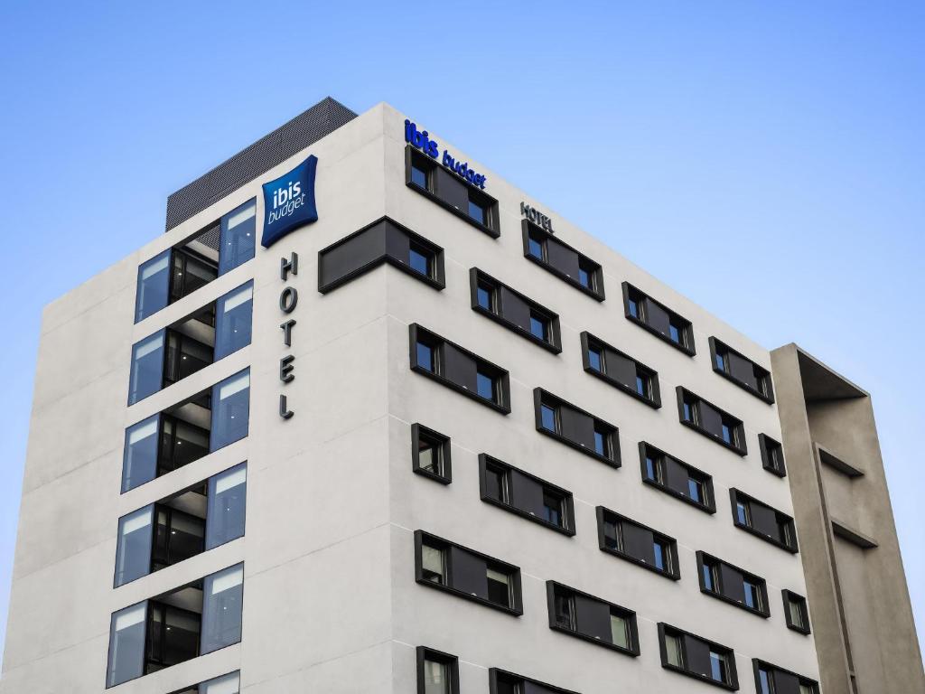 a tall white building with a sign on it at ibis budget Santiago Providencia in Santiago
