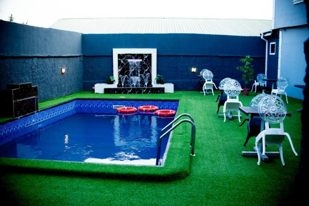 einen Hinterhof mit einem Pool mit grünem Gras in der Unterkunft Ivy Hotel Epe in Poka