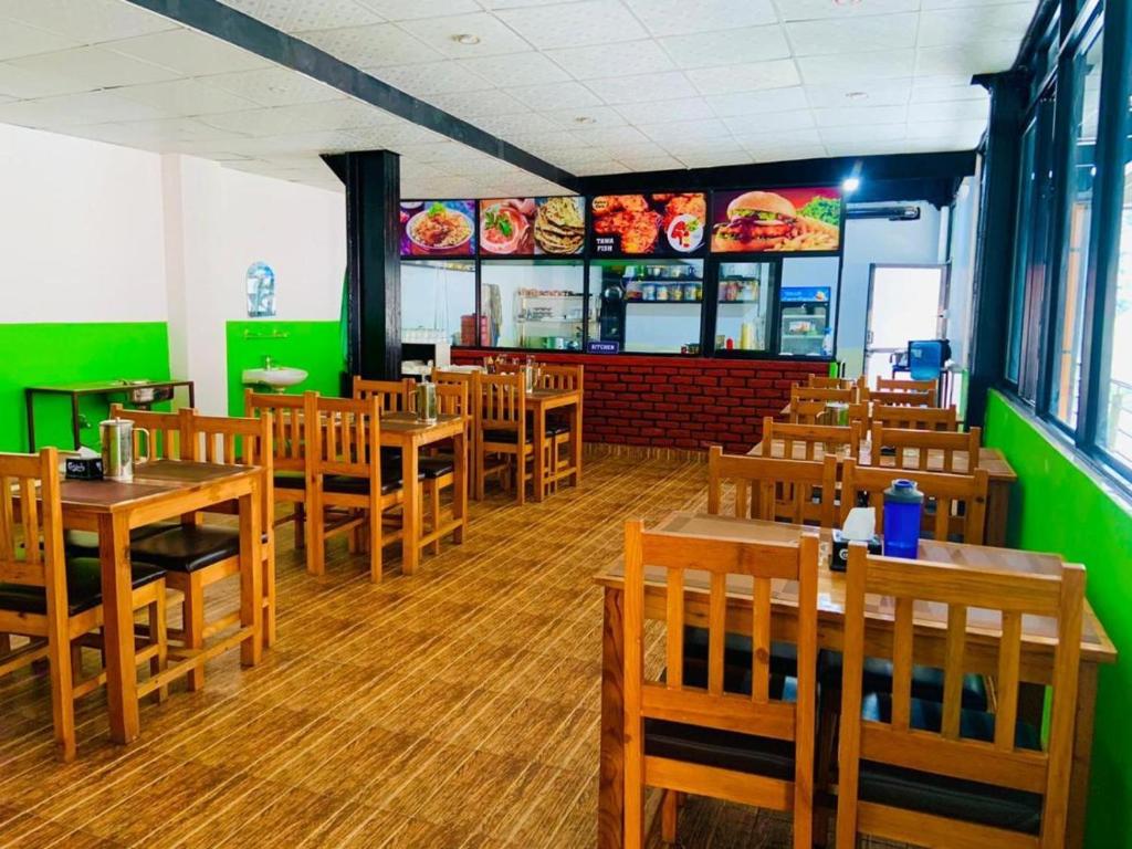 um restaurante com mesas e cadeiras de madeira e paredes verdes em Hotel Good one em Pokhara