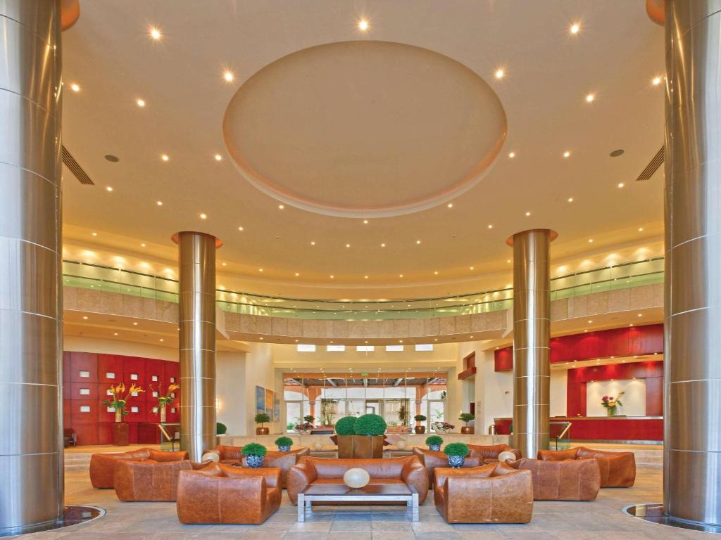un hall d'entrée avec des canapés et un grand miroir au plafond dans l'établissement Mövenpick Resort El Sokhna, à Ain Sokhna